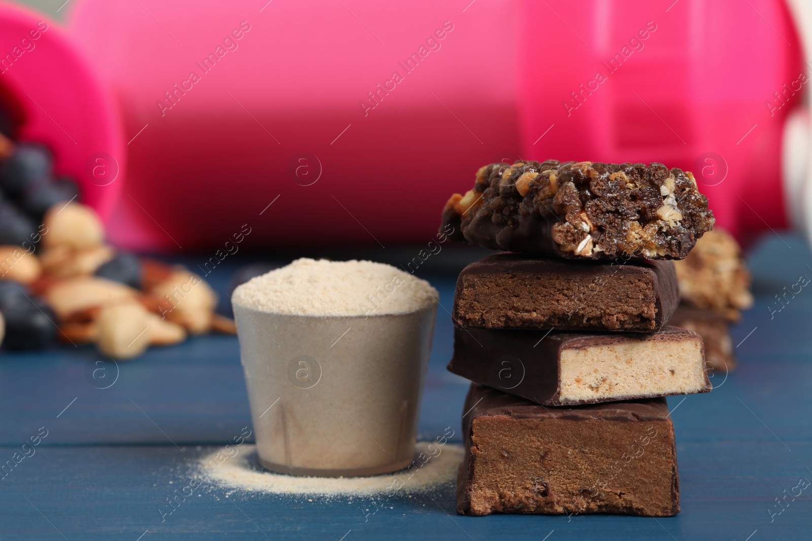 Photo of Different energy bars and protein powder on blue wooden table, closeup
