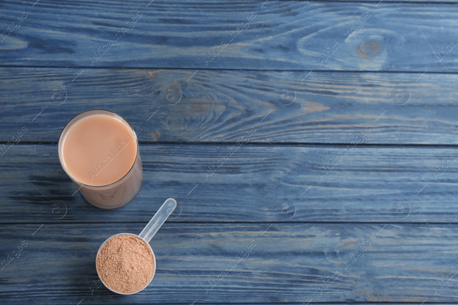 Photo of Protein shake and powder on blue wooden table, flat lay. Space for text