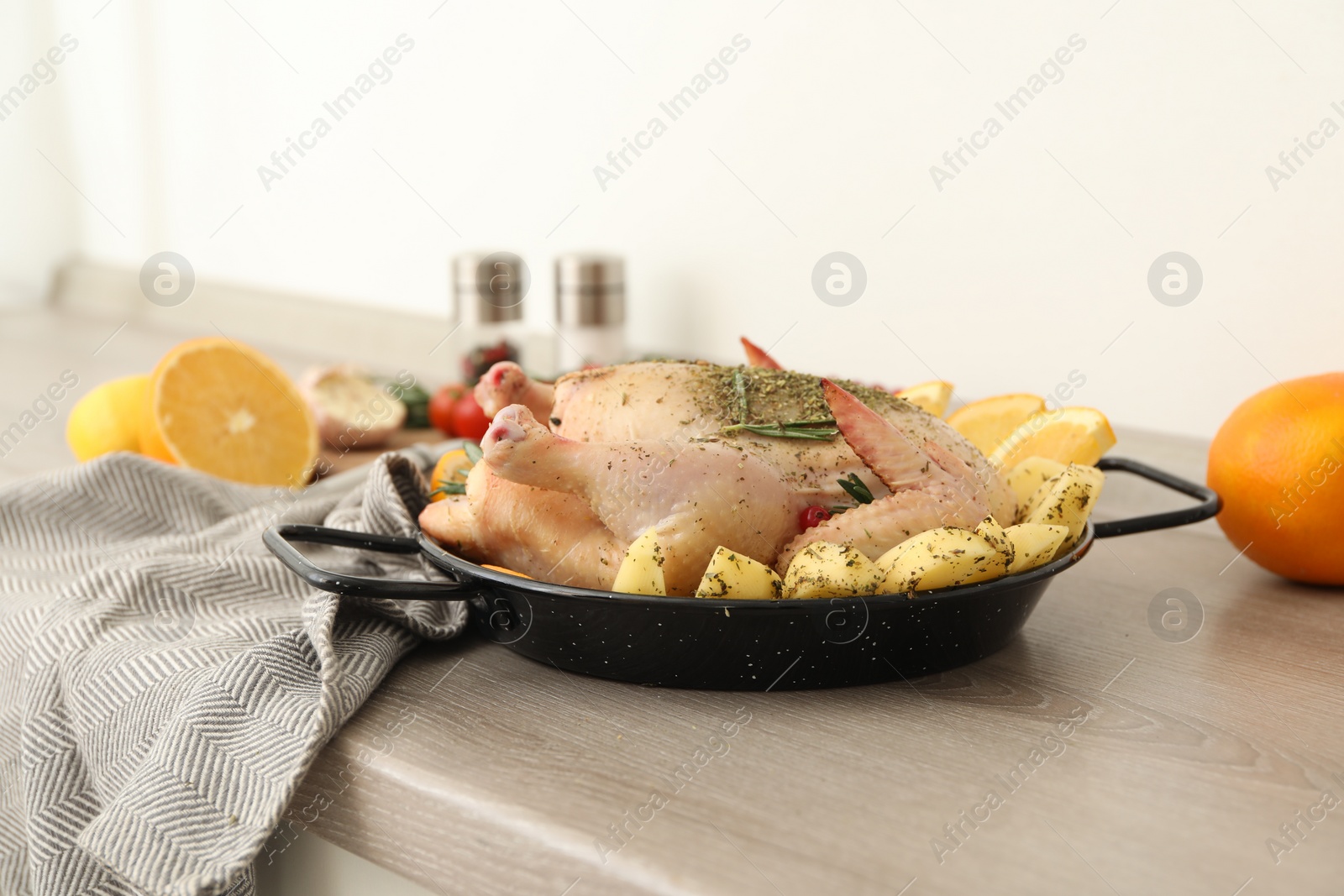 Photo of Chicken with orange and potato slices in baking pan on wooden table