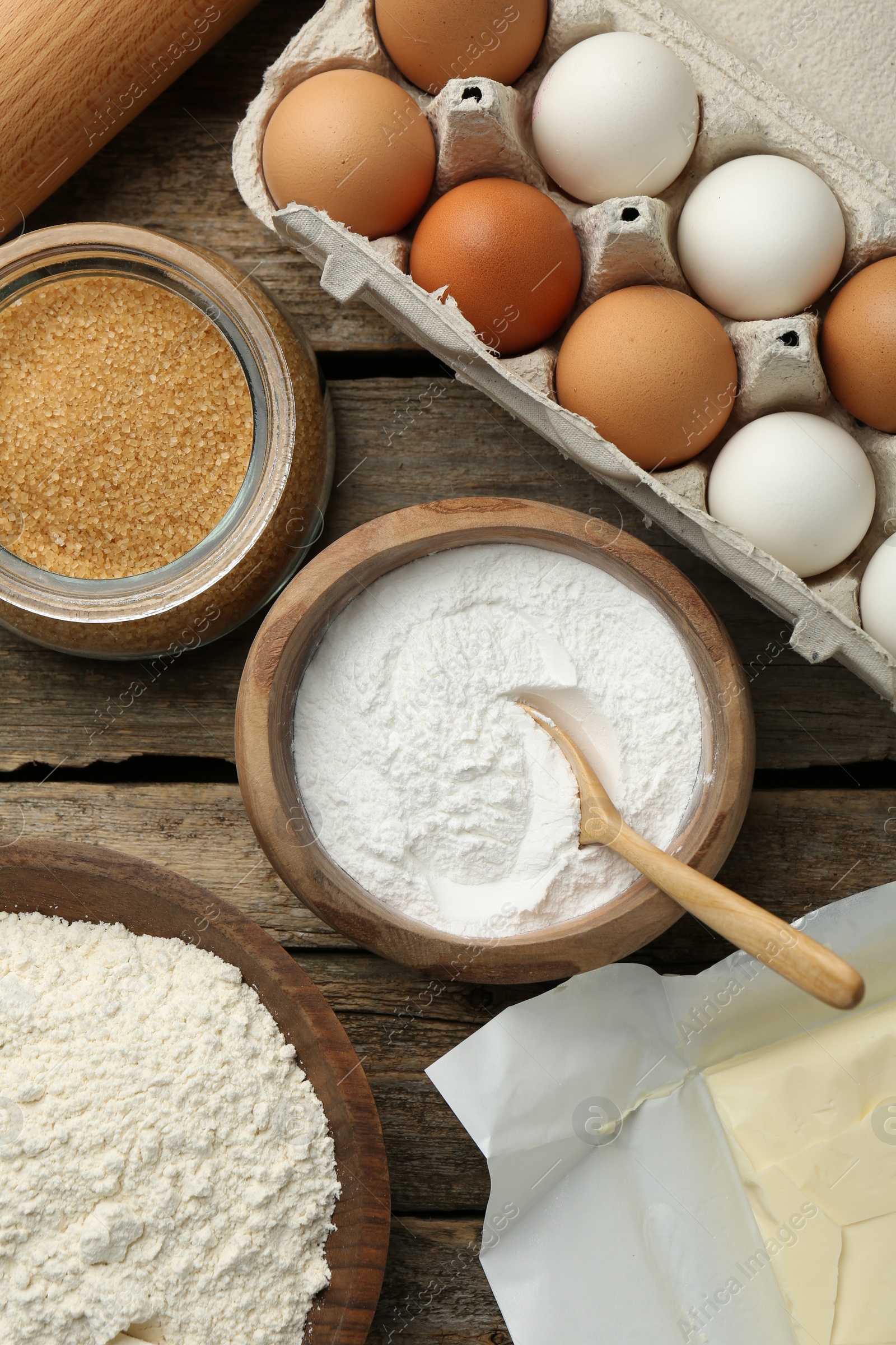 Photo of Baking powder and other ingredients for making dough on wooden table, flat lay