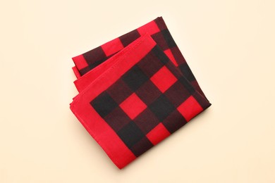Photo of Folded red checkered bandana on beige background, top view