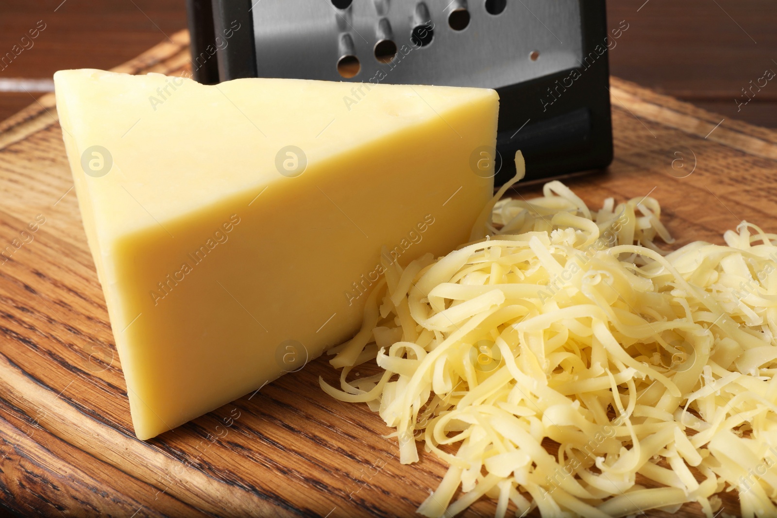 Photo of Grated and whole piece of cheese on wooden board, closeup