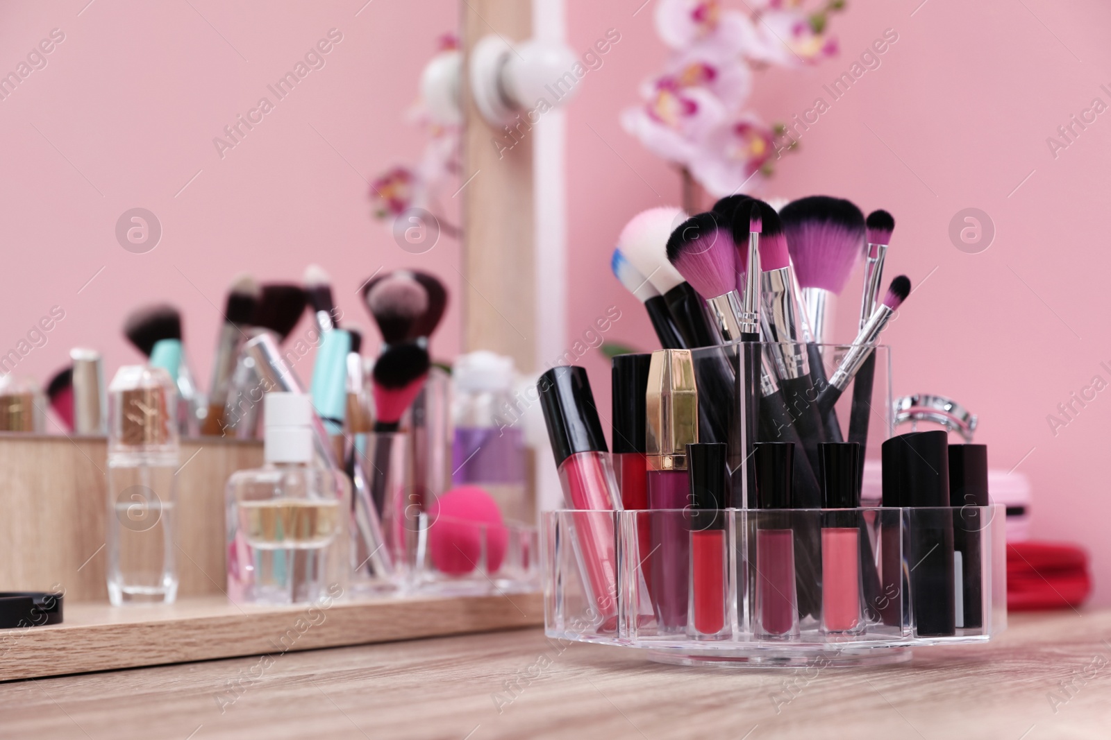 Photo of Organizer with cosmetic products for makeup on table near mirror. Space for text