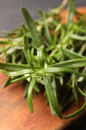 Photo of Fresh green rosemary on wooden board, closeup