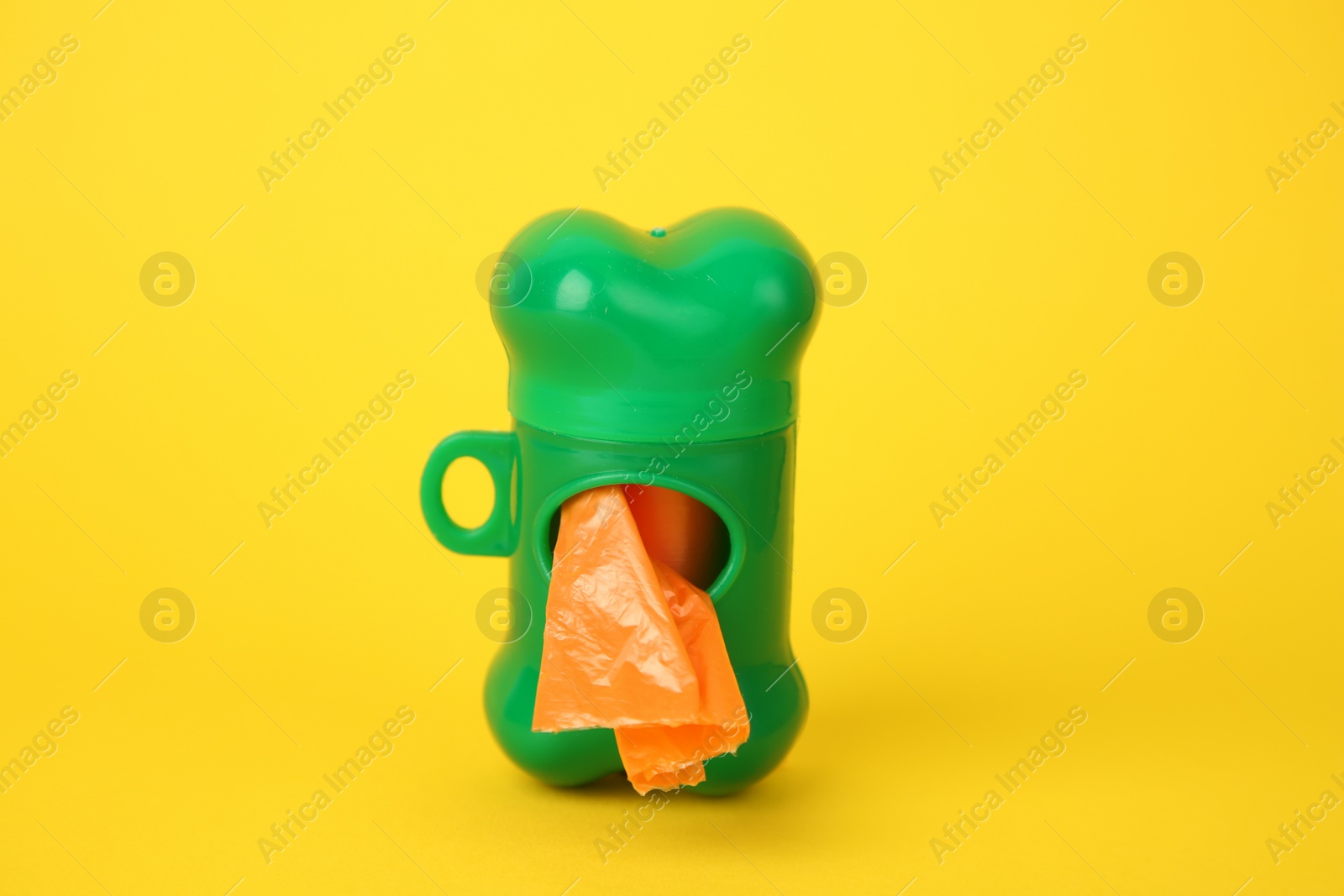 Photo of Dispenser with dog waste bags on yellow background