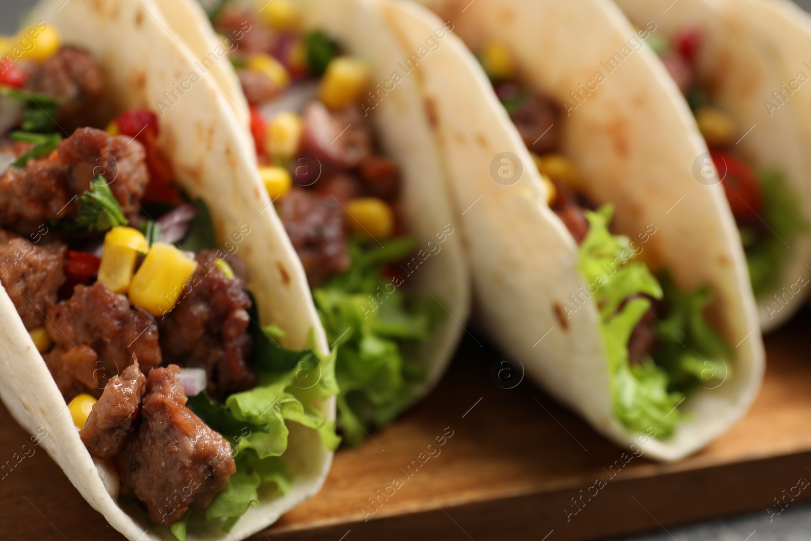 Photo of Delicious tacos with meat and vegetables on table, closeup