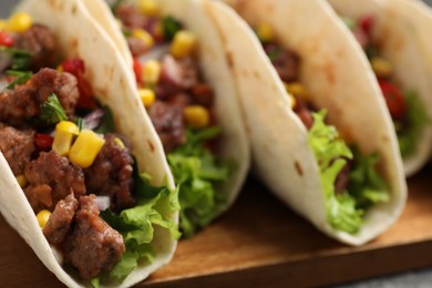 Photo of Delicious tacos with meat and vegetables on table, closeup