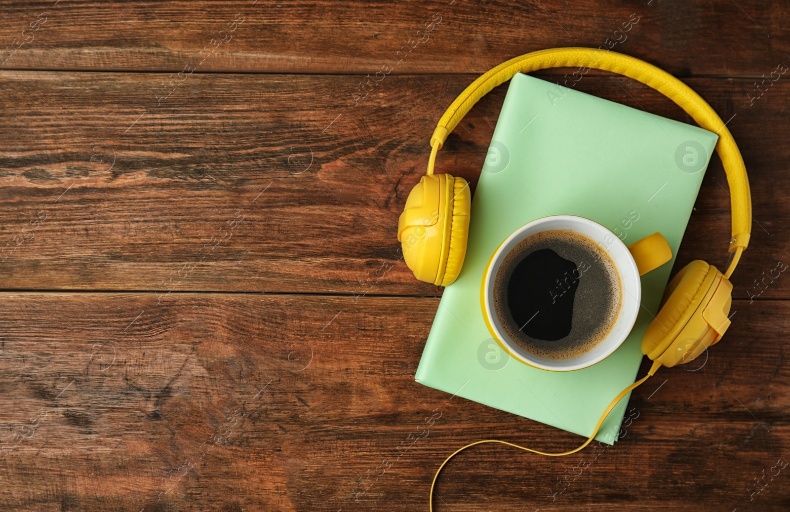 Photo of Book, coffee and headphones on wooden table, top view. Space for text