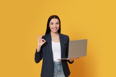 Young woman with modern laptop on yellow background