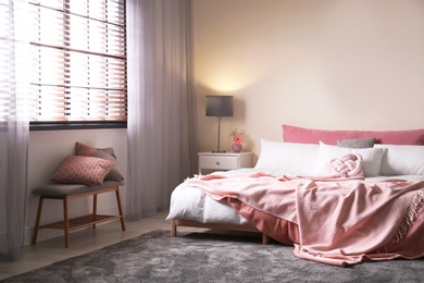 Modern room interior with comfortable double bed and window blinds