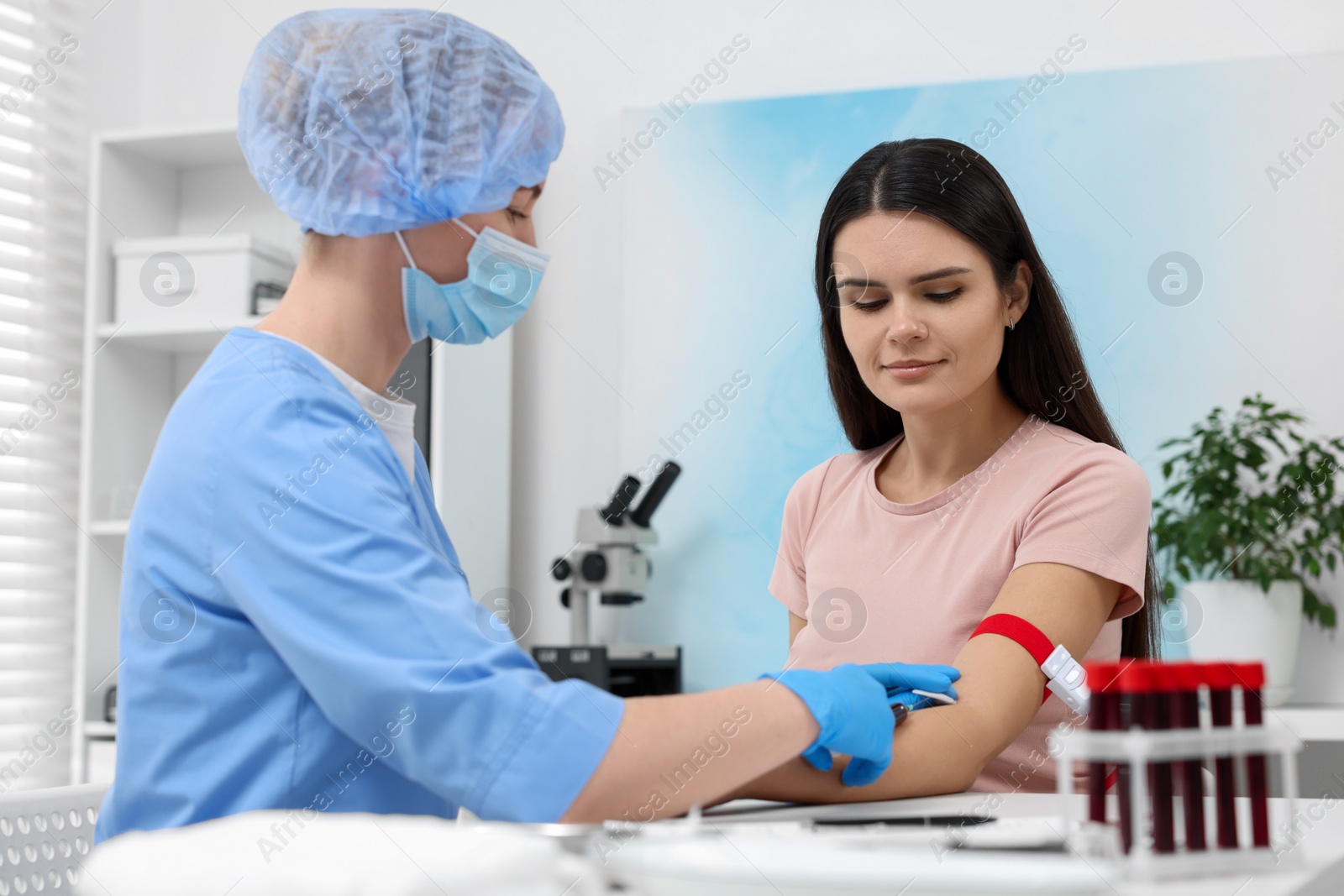 Photo of Laboratory testing. Doctor taking blood sample from patient at white table in hospital