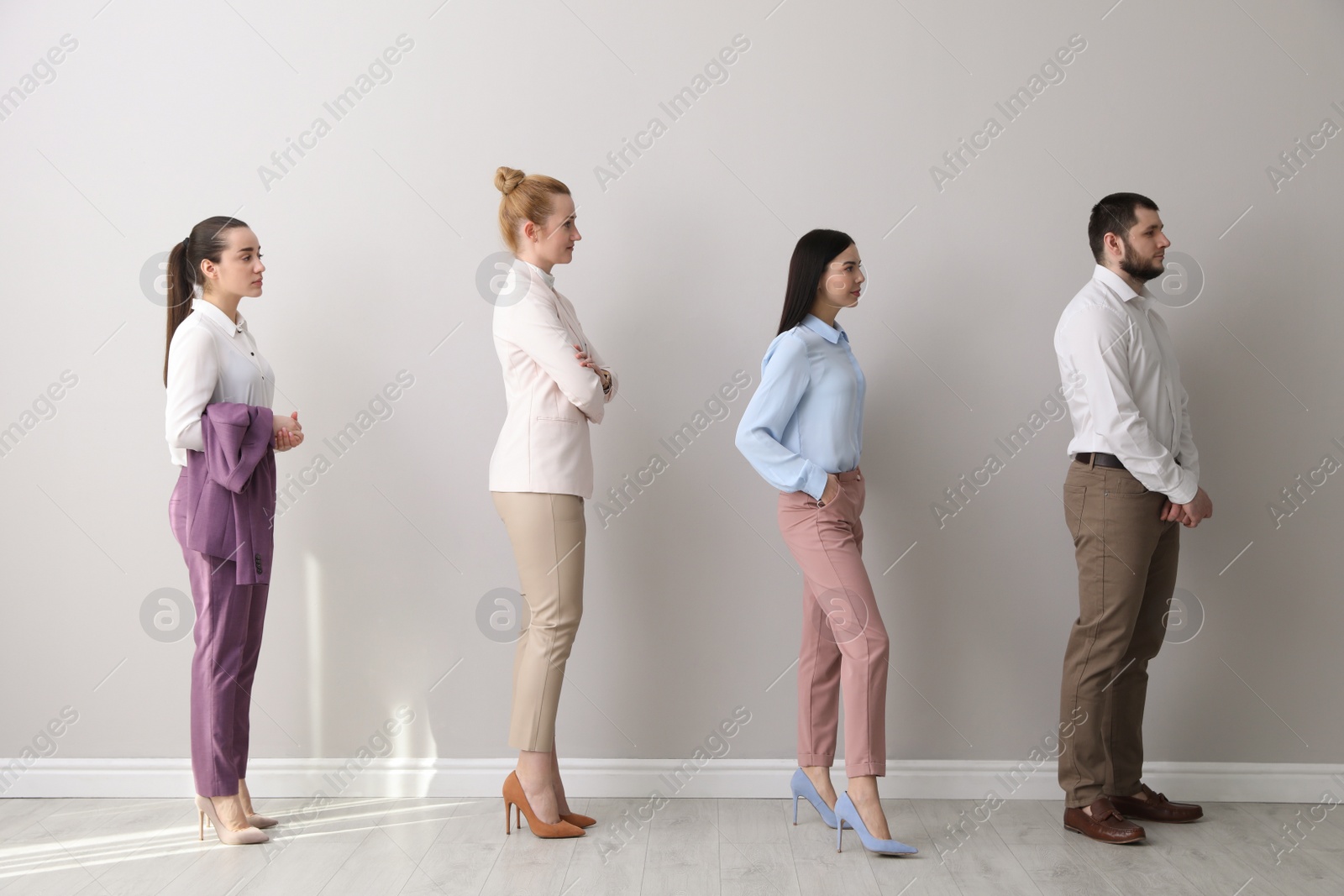 Photo of Businesspeople waiting in queue near light wall indoors