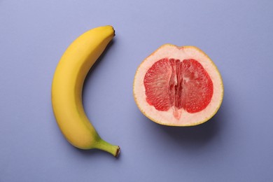 Photo of Banana and half of grapefruit on violet background, flat lay. Sex concept