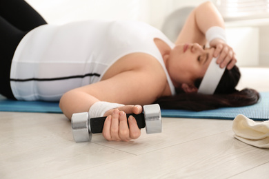 Photo of Lazy overweight woman resting instead of training at gym, focus on dumbbell