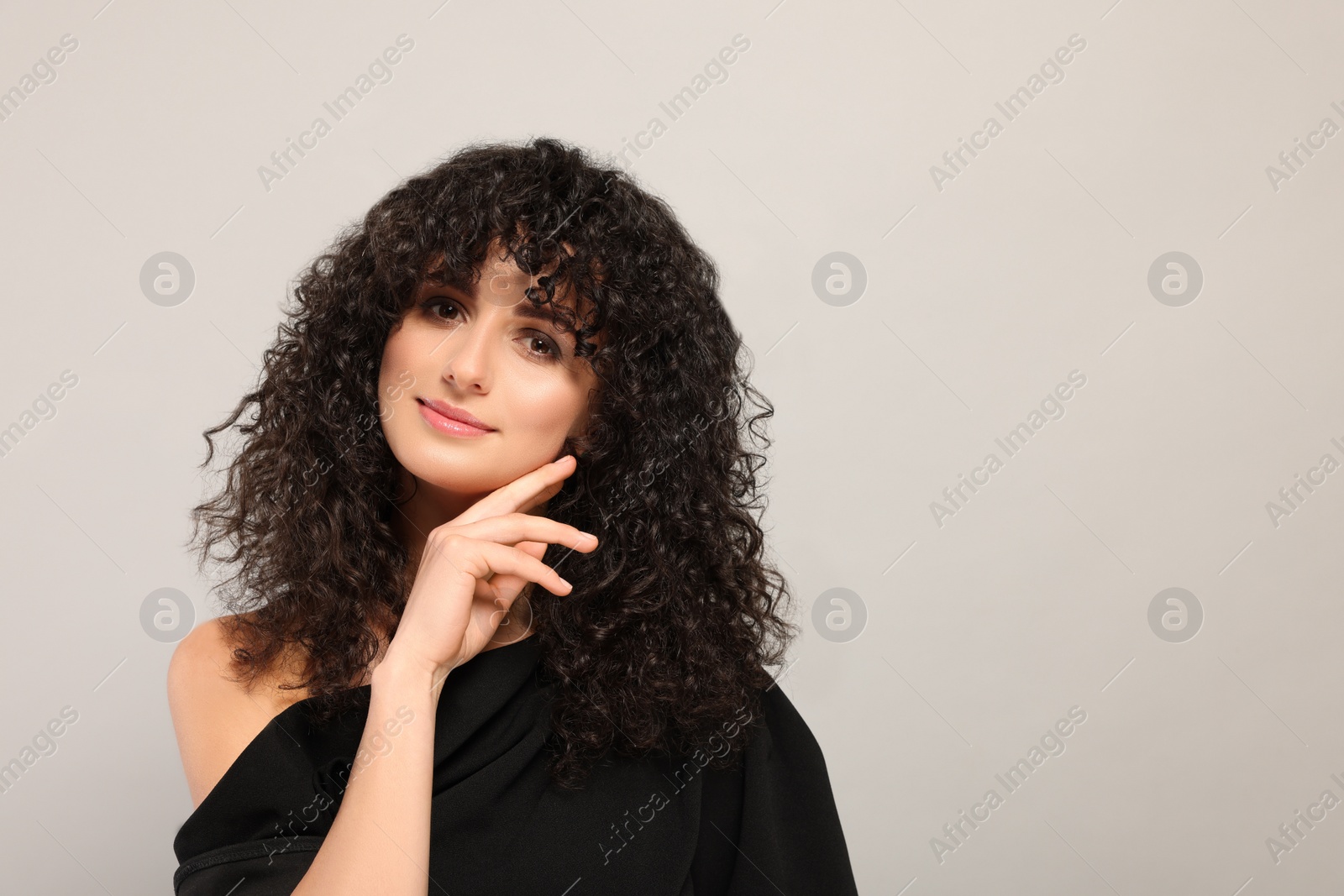 Photo of Beautiful young woman with long curly hair on light grey background. Space for text