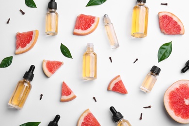 Composition with grapefruit slices and bottles of essential oil on white background, top view