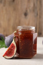 Jar of tasty sweet jam and fresh figs on white wooden table