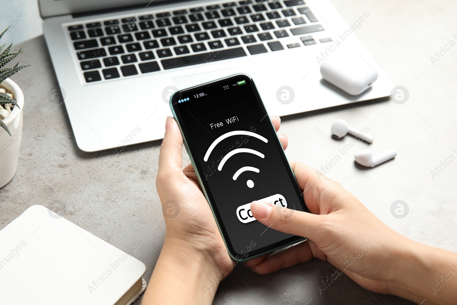 Image of Woman connecting to WiFi using mobile phone at table, closeup