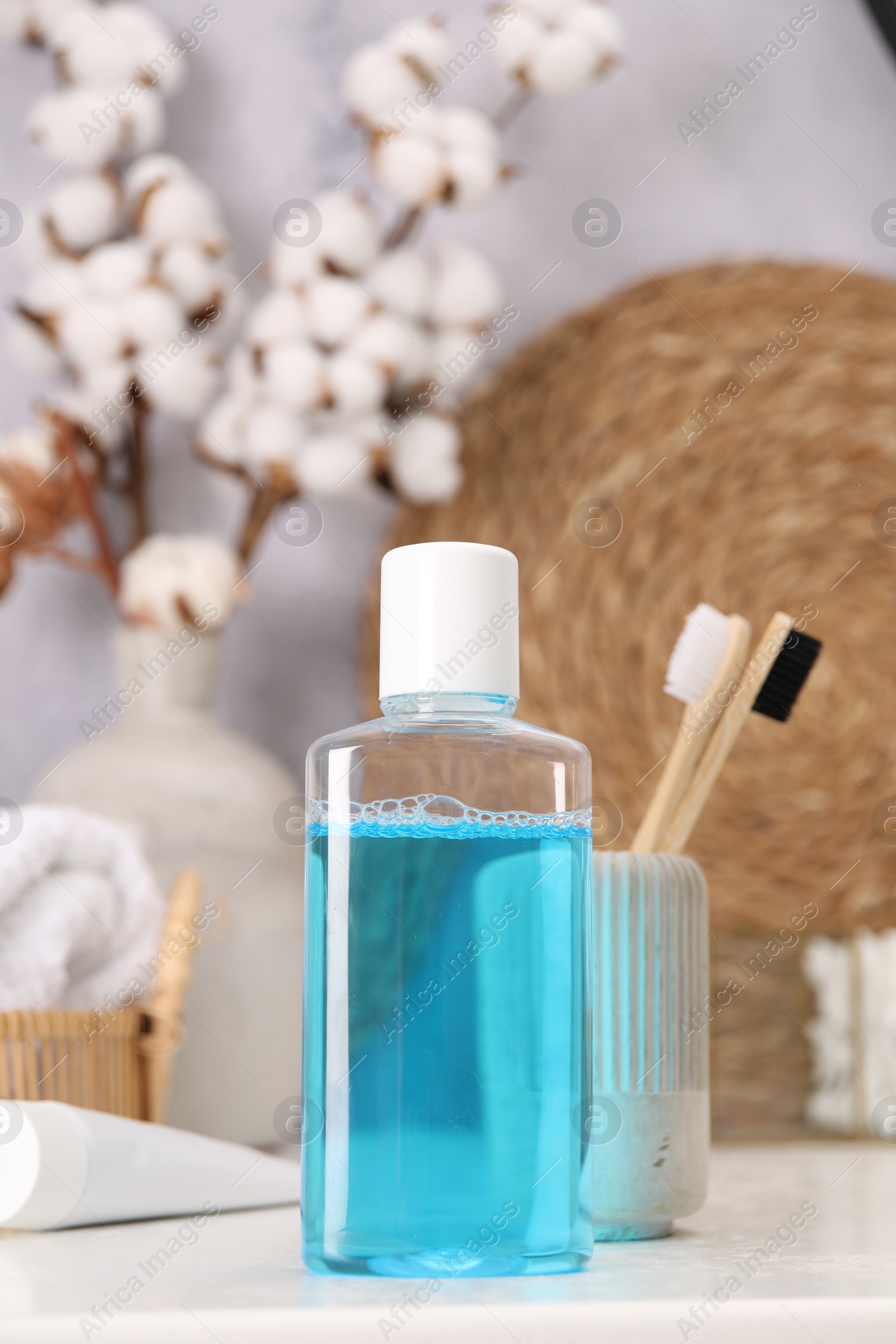 Photo of Bottle of mouthwash and toothbrushes on white table in bathroom