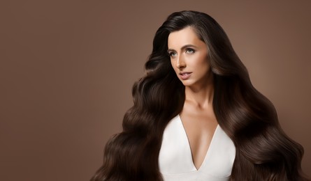 Image of Hair styling. Attractive woman with wavy long hair on brown background. Banner design with space for text