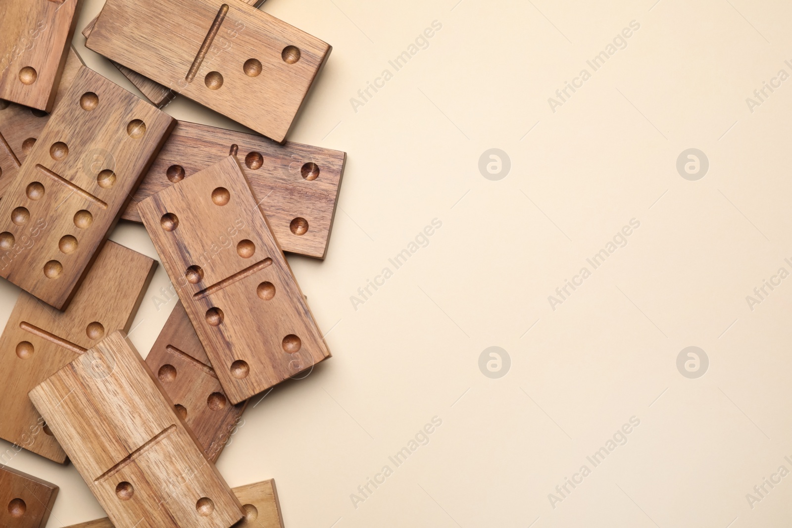 Photo of Wooden domino tiles on beige background, flat lay. Space for text