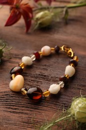 Photo of Beautiful bracelet with gemstones and flowers on wooden table
