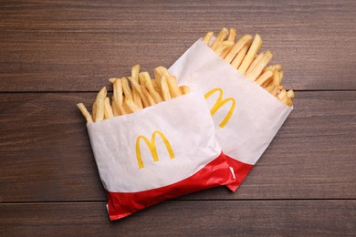 MYKOLAIV, UKRAINE - AUGUST 12, 2021: Two small portions of McDonald's French fries on wooden table, flat lay