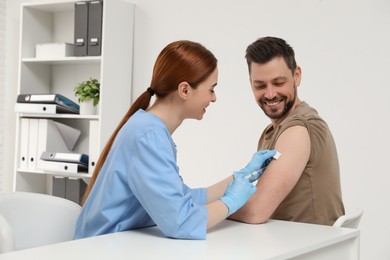 Doctor giving hepatitis vaccine to patient in clinic