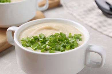 Photo of Bowl with tasty creamy soup of parsnip on light grey table, closeup