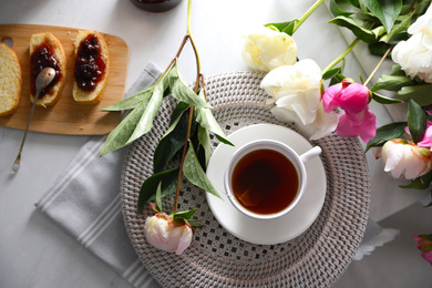 Photo of Beautiful peonies and breakfast on marble table, flat lay