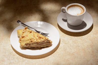 Photo of Piece of delicious cake and coffee on beige table