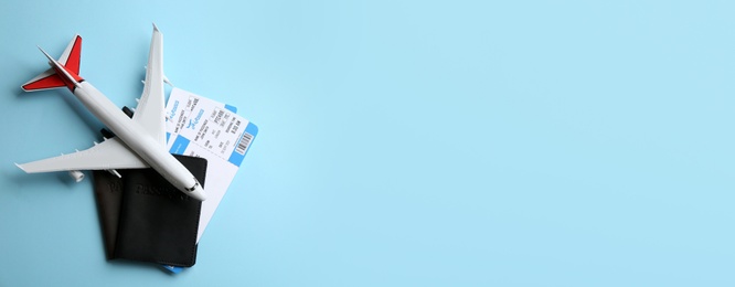 Photo of Toy airplane and passports with tickets on light blue background, flat lay. Space for text