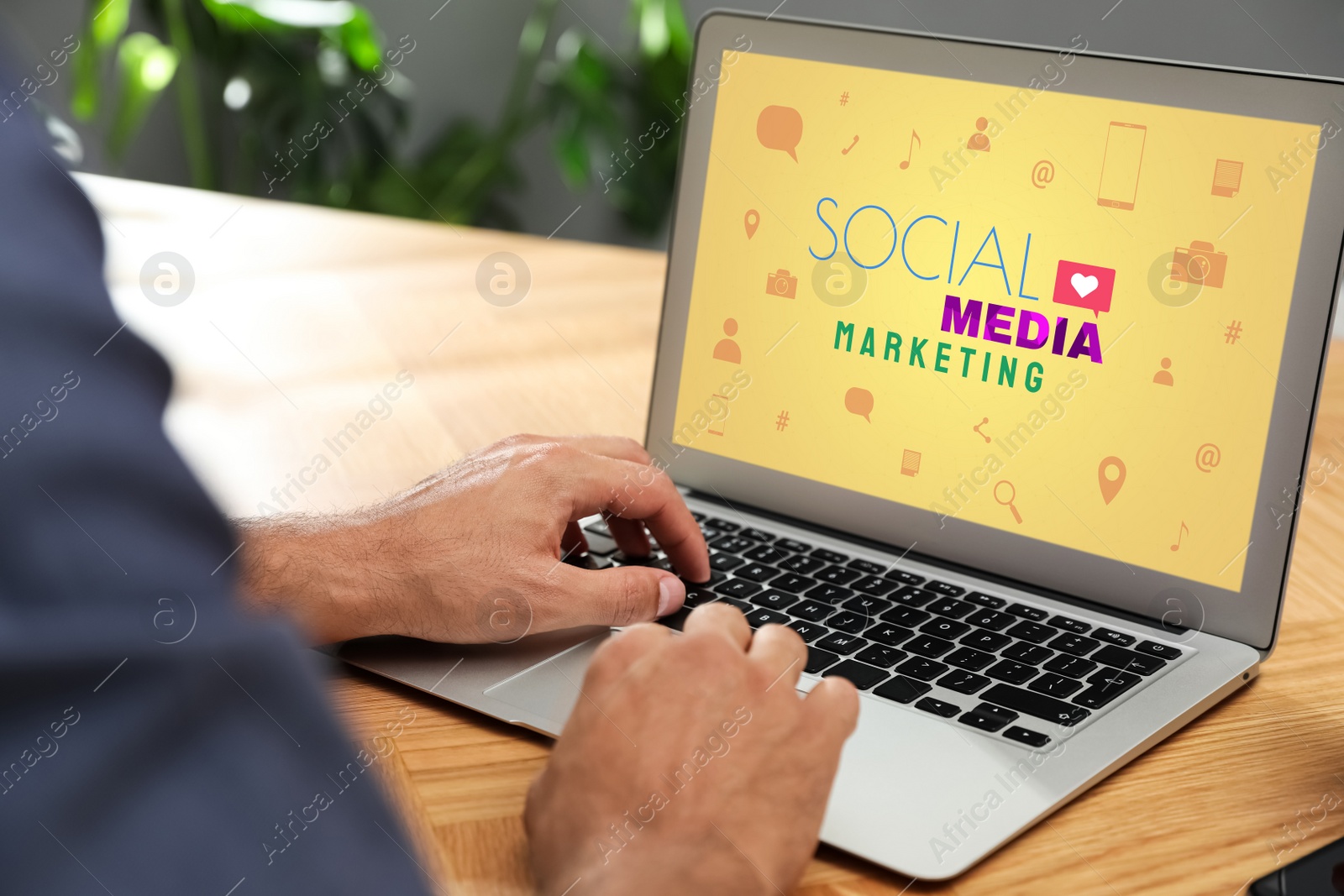 Image of SMM (Social Media Marketing) concept. Man using laptop at wooden table indoors, closeup