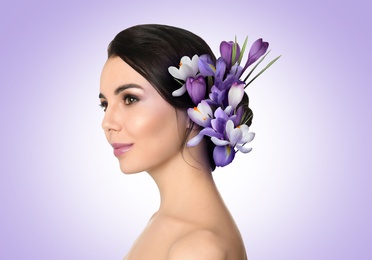 Image of Pretty woman wearing beautiful wreath made of flowers on light violet background