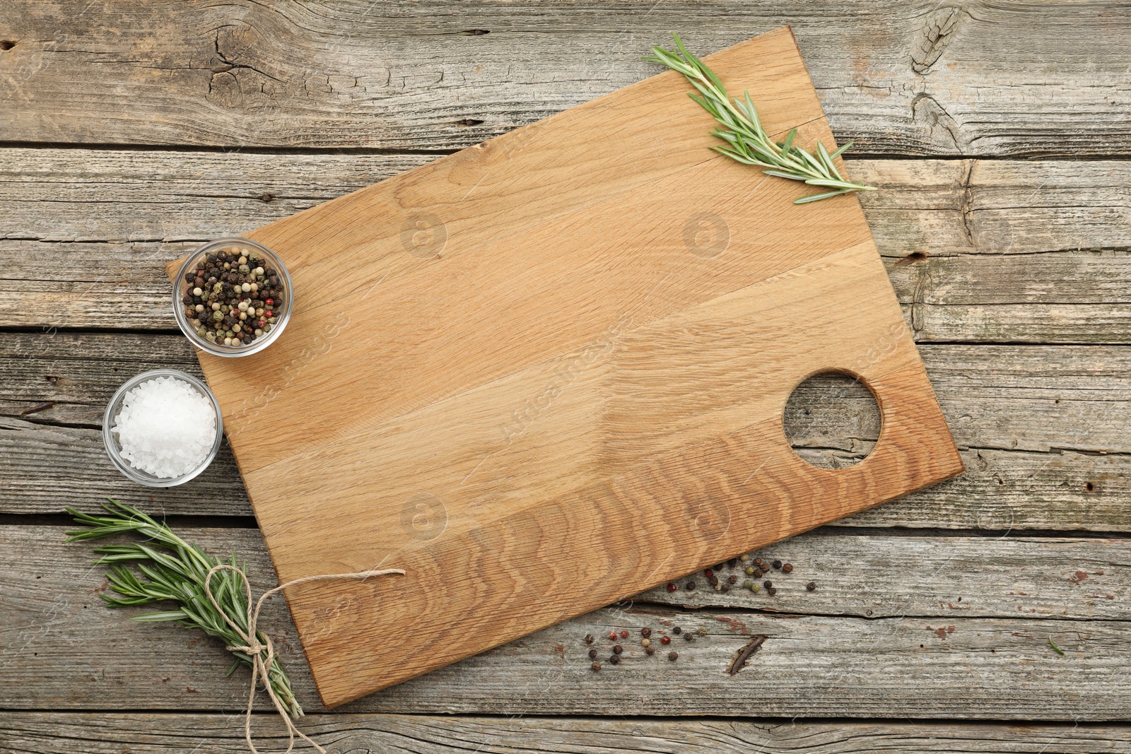 Photo of Cutting board, rosemary, salt and pepper on wooden table, flat lay. Space for text