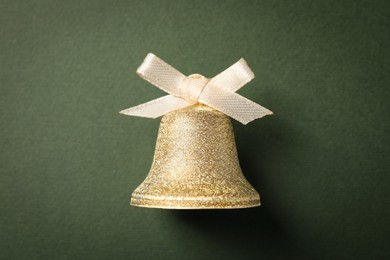 Photo of Bell with bow on dark green background, top view. Christmas decor