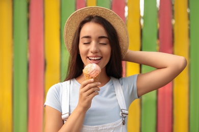 Photo of Happy young woman with delicious ice cream in waffle cone outdoors