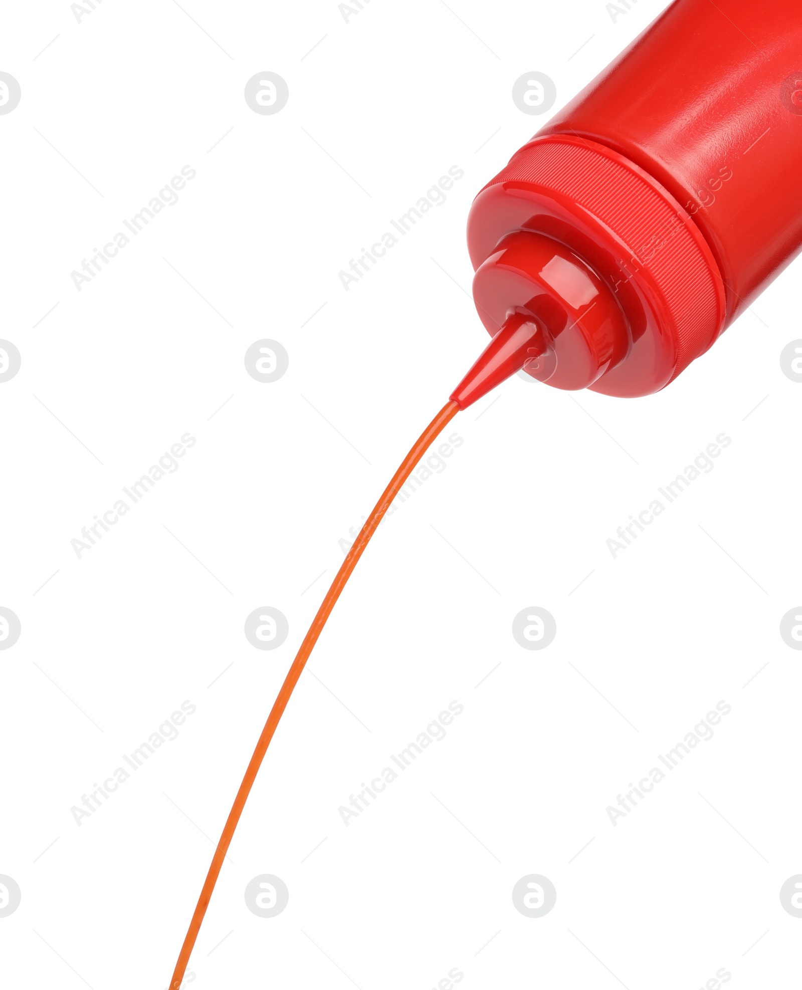 Photo of Pouring tasty red ketchup from bottle isolated on white