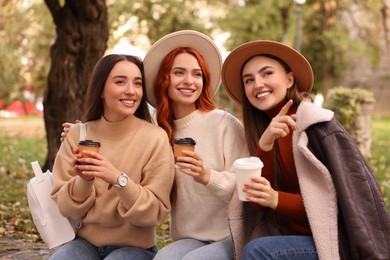 Photo of Happy friends with paper cups of coffee in park
