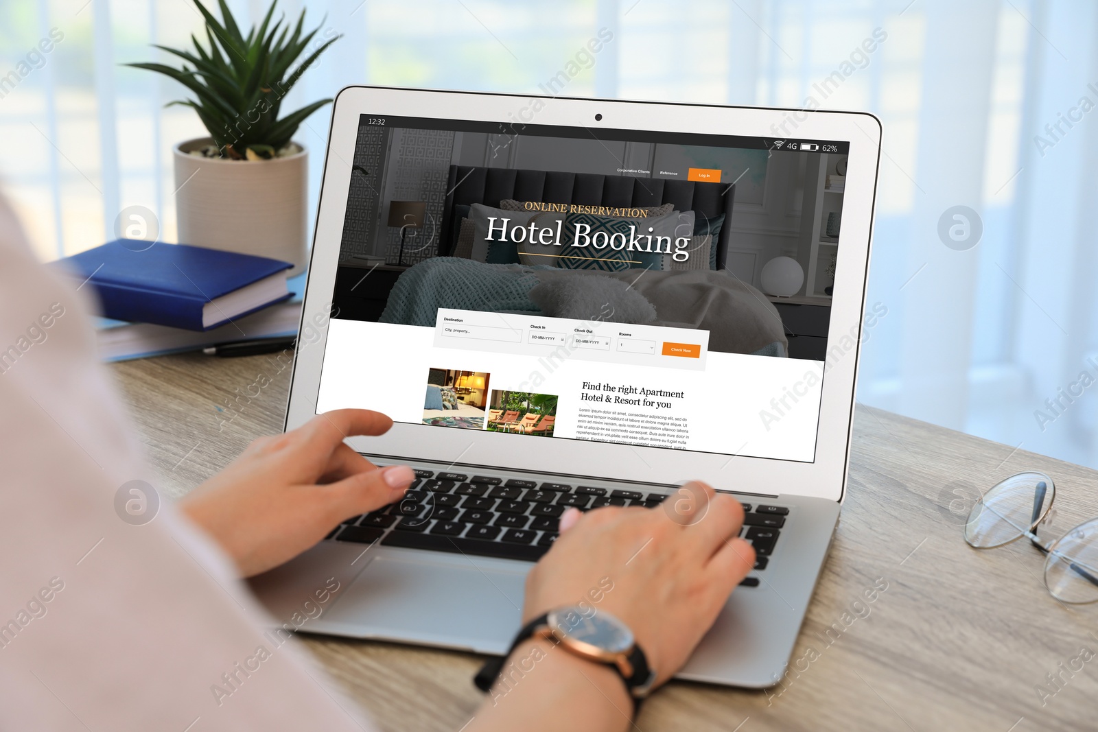 Image of Woman using laptop to book hotel at wooden table, closeup