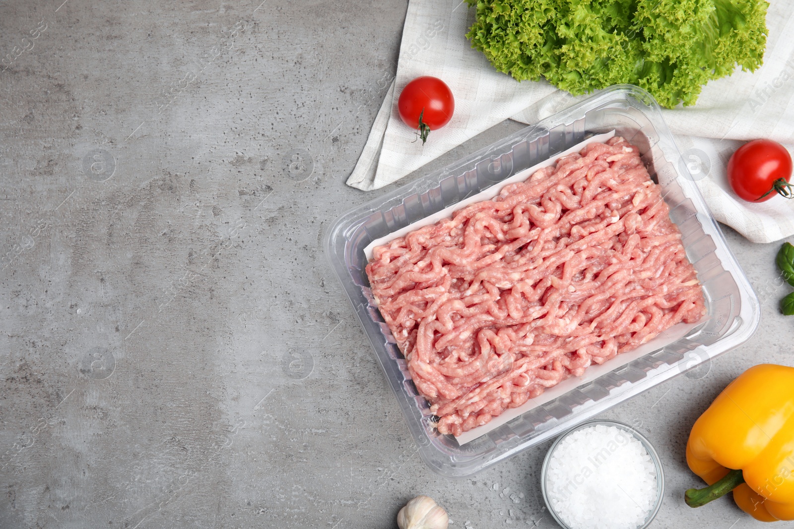 Photo of Raw chicken minced meat and ingredients on grey table, flat lay. Space for text