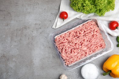 Photo of Raw chicken minced meat and ingredients on grey table, flat lay. Space for text