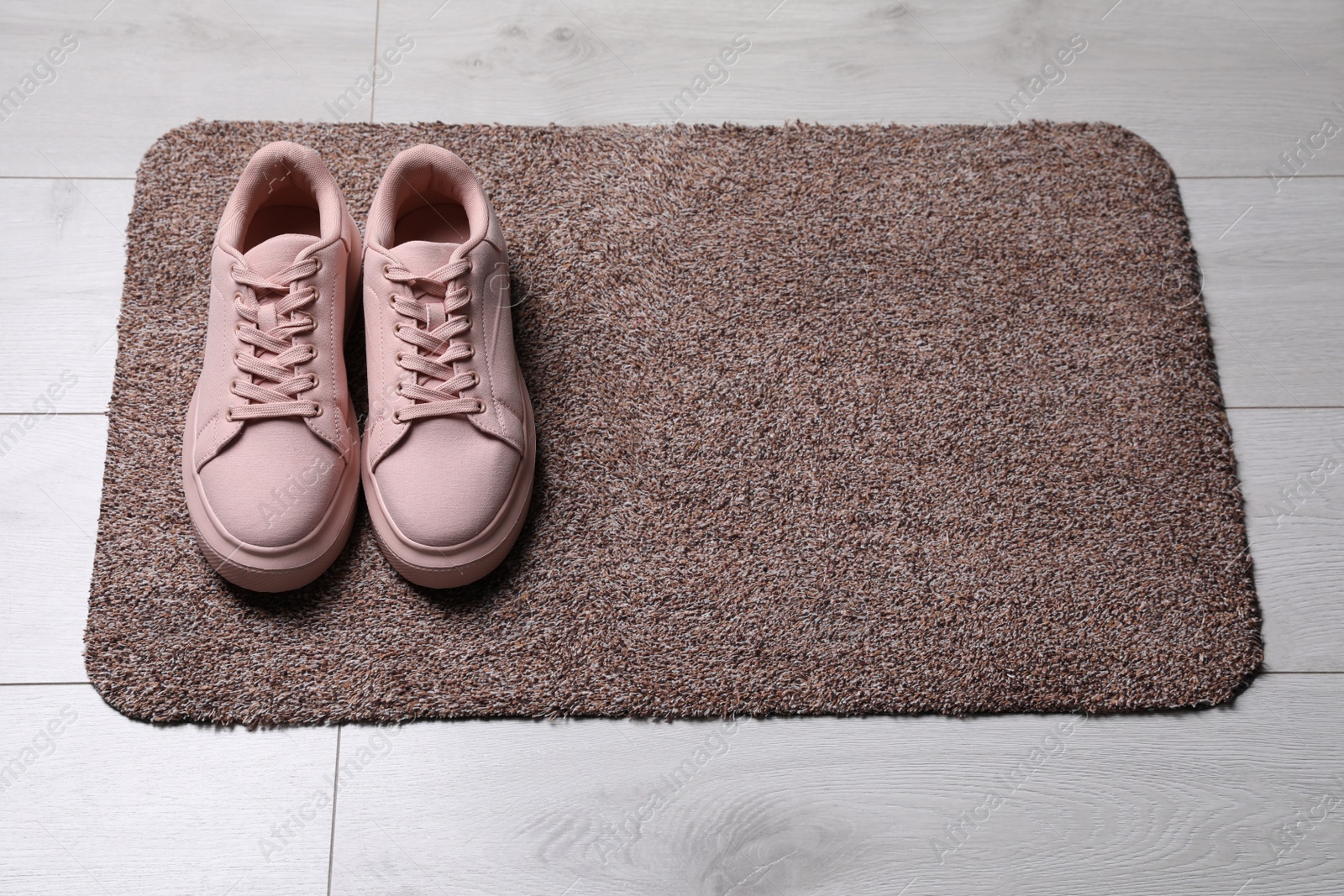 Photo of New clean door mat with shoes on floor