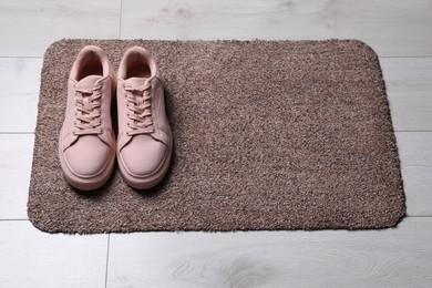 New clean door mat with shoes on floor