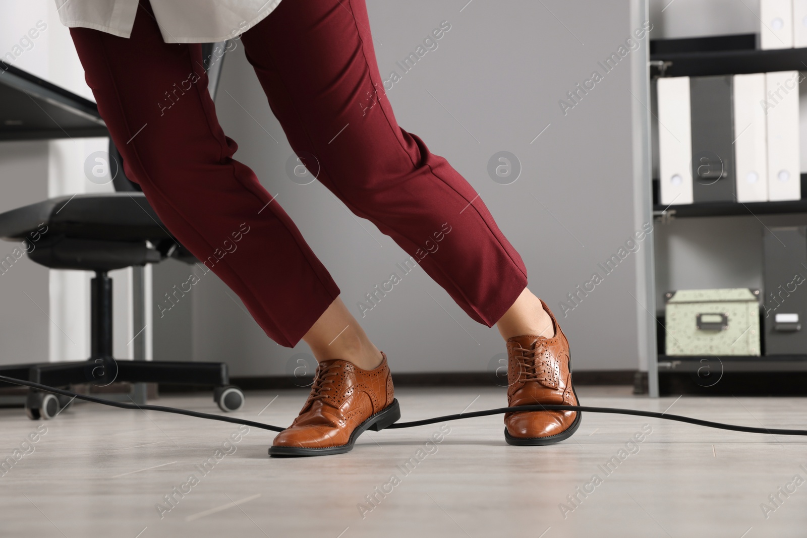 Photo of Woman tripping over cable in office, closeup