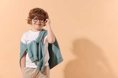 Photo of Fashion concept. Stylish boy on pale orange background. Space for text
