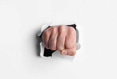 Man breaking through white paper with fist, closeup