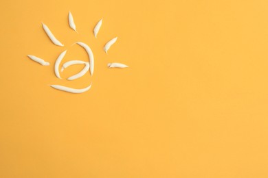 Photo of Drawing of sun with cream on orange background, top view and space for text. Skin care and protection