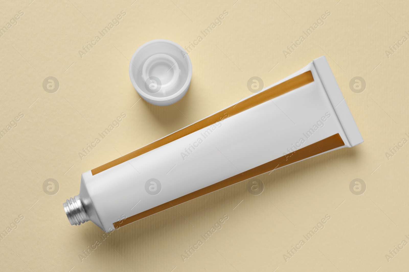 Photo of Open tube of ointment on beige background, flat lay. Space for text