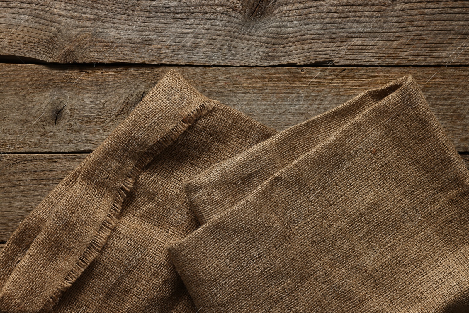 Photo of Burlap fabric on wooden table, top view